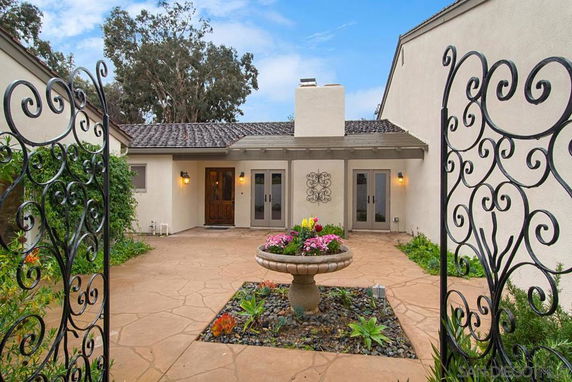 Front view of a house with a courtyard and decorative iron gates.