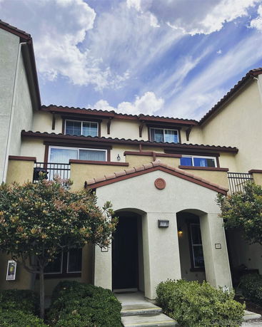 Front view of a multi-story house with arched entryway and balconies.