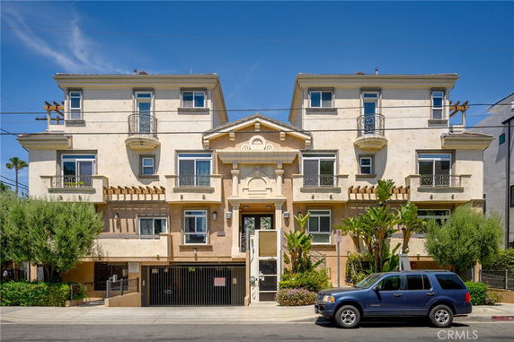 Front view of a multi-story residential building with balconies and decorative elements.