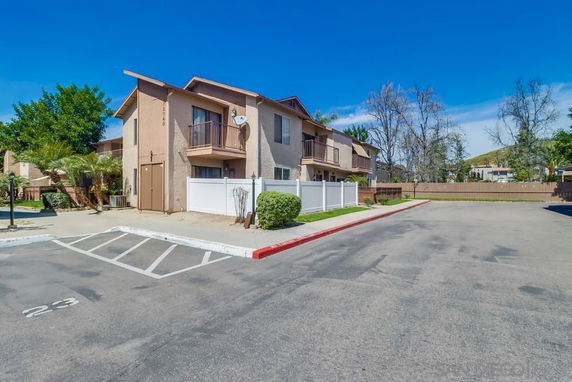 Front view of a two-story residential building with a parking area in front.