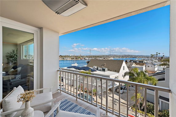 Balcony view overlooking houses, marina, and distant shoreline.