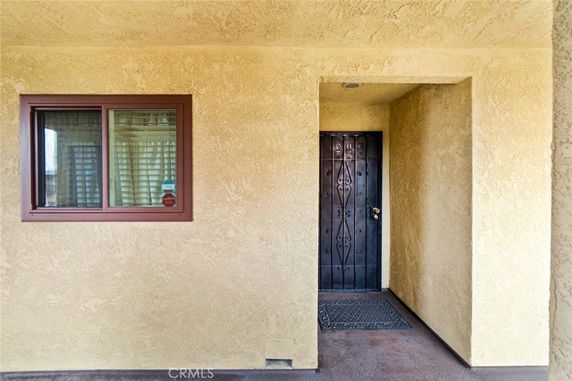 Front view of a house with a black door and a window on a textured wall.