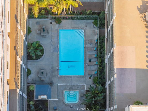 Aerial view of a rectangular swimming pool with lounge chairs and surrounding greenery.