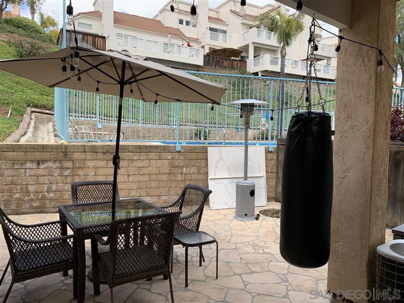 Outdoor patio area with table, umbrella, and punching bag, with view of residential buildings.