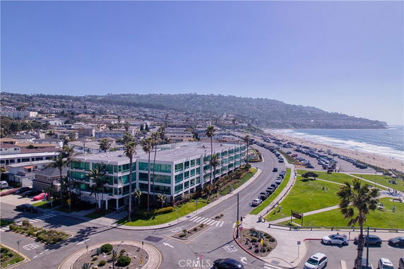 Wide-angle view of a coastal area with a large building near the beach and a scenic road.