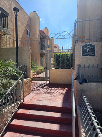 Exterior view of a building entrance with a gated staircase and surrounding walls.