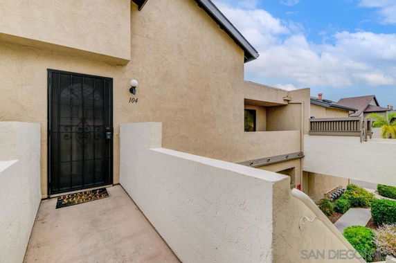 Front view of a condominium entrance with beige stucco walls and a black security door.