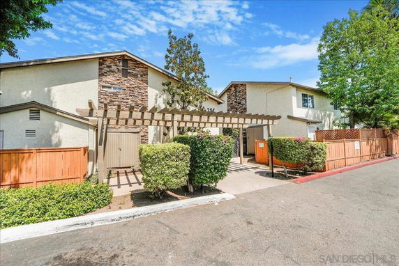 Front view of a two-story house with a wooden fence and a trellis.