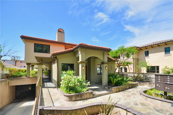 Front view of a two-story house with an arched entrance and a tile roof.