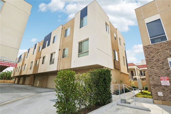 Front view of a three-story residential building with garage doors at the ground level.