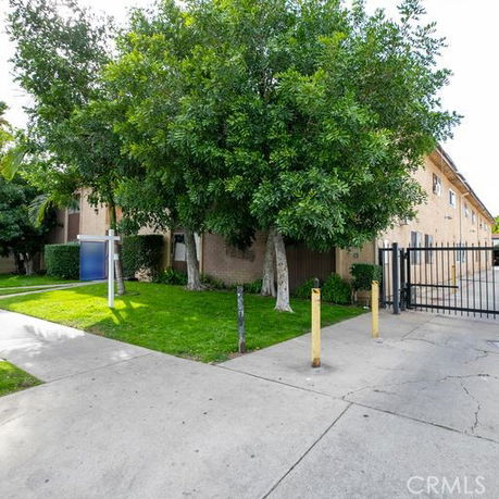 Front view of a residential building with gated entry and surrounding greenery.