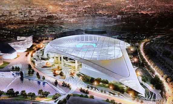 Aerial view of a large, modern stadium with a unique roof design, surrounded by urban landscape.