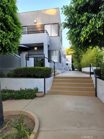 Front view of a modern two-story building with a small staircase and railing.