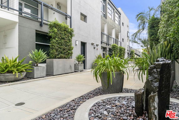 View of modern building exterior with greenery and large planters in the courtyard.