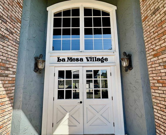 Front view of a building entrance with double doors and the name 'La Mesa Village' above.