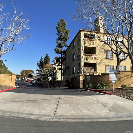 Front view of a multi-story residential building with balconies and gated entry.