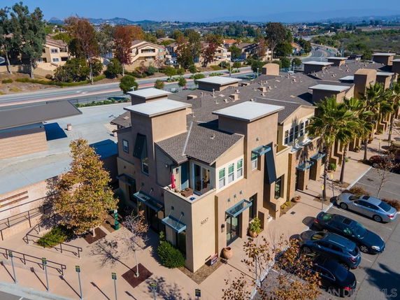 Aerial view of a commercial building with multiple entrances and parking area in front.