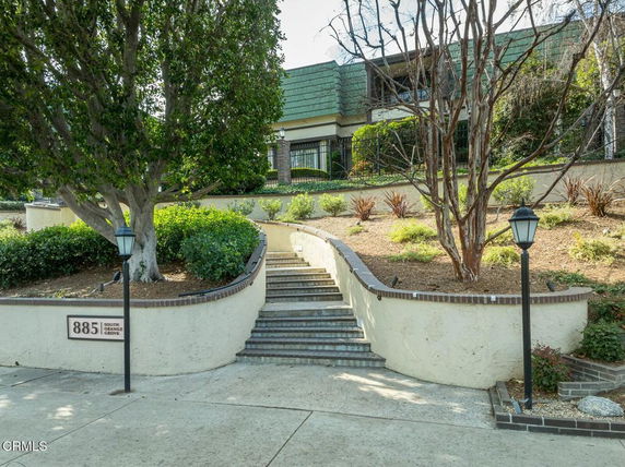 Front view of a multi-story building with landscaped steps leading up to it.