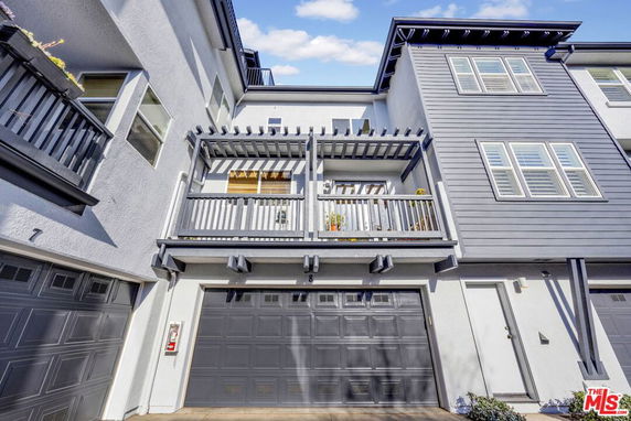 Front view of a multi-story house with a balcony and garage doors.