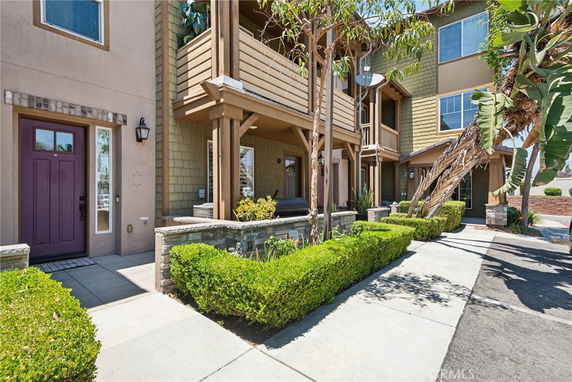 Front view of a multi-story townhouse with balconies and landscaped entrance.