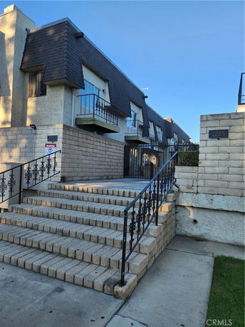 Front view of a multi-story building with sloped roofs and external staircases.