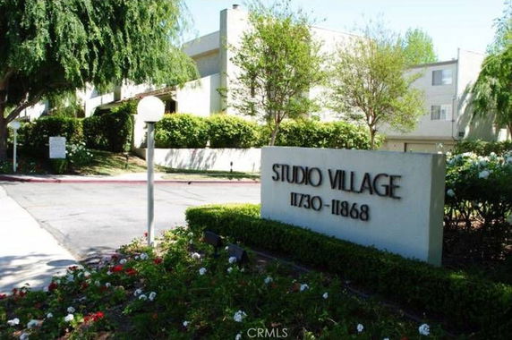 Front view of a multi-story residential building with a sign saying 'Studio Village'.