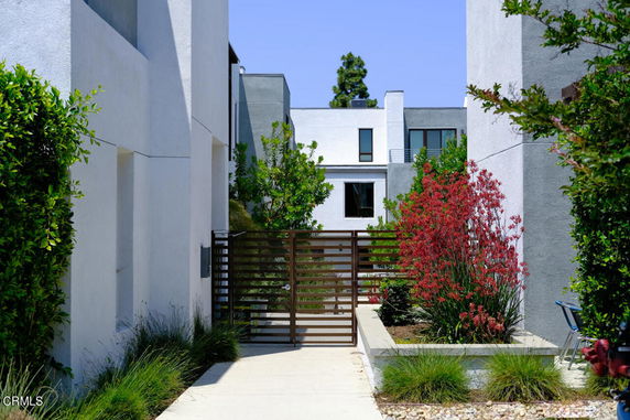 Front view of a modern multi-story building with a gate and landscaping.