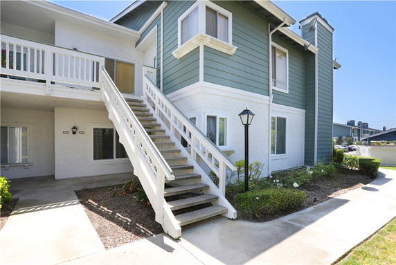 Front view of a two-story building with an external staircase and green siding.