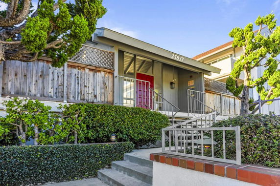 Front view of a house with a staircase leading to a red front door.