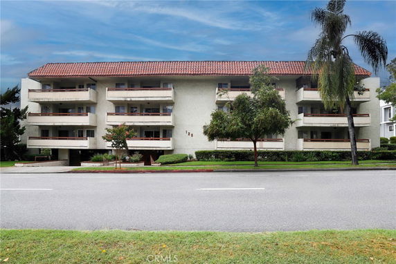 Front view of a multi-story residential building with balconies and a red-tiled roof.