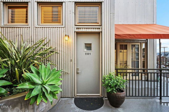 Front view of a building entrance with number 201 and potted plants.