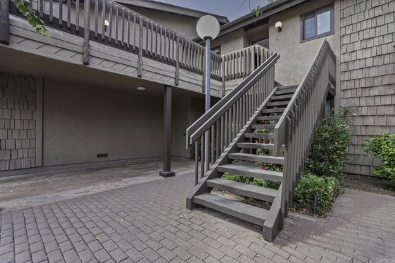 Exterior view of a building with an elevated walkway and stairs.