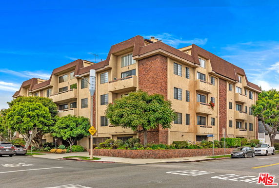 Front view of a multi-story residential building with beige and brick exterior.