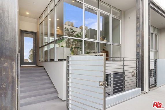 Front view of a modern building entrance with glass windows and a metal gate.