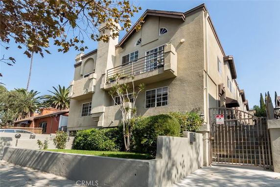 Front view of a multi-story residential building with balconies and gated entrance.
