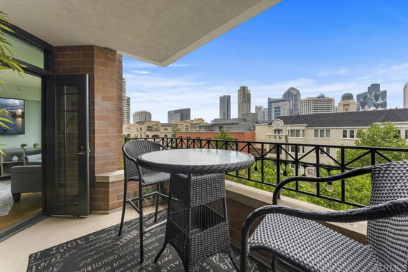 Rooftop terrace with a view of a city skyline, featuring a round table and chairs.
