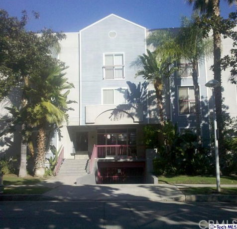Front view of a multi-story residential building with balconies and entrance stairs.
