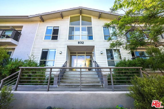 Front view of a multi-story building with balconies and stairway entrance.