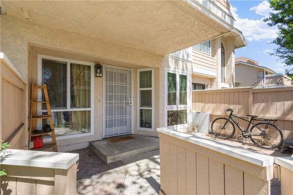 Front view of a house entrance with a metal screen door and surrounding windows.