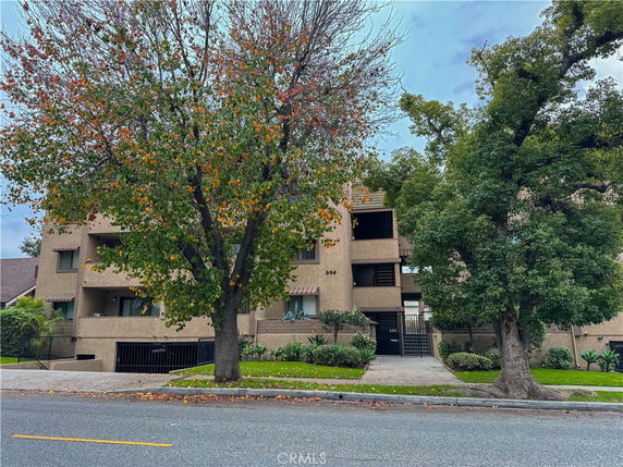 Front view of a multi-story building with balconies and a gated entrance.