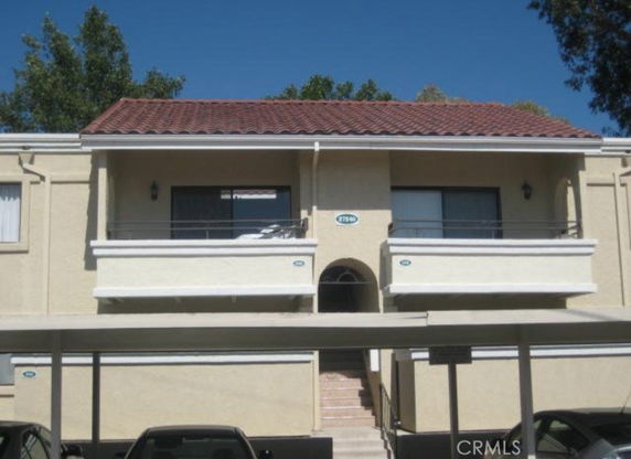 Front view of a two-story building with a stairway entrance and a red-tile roof.
