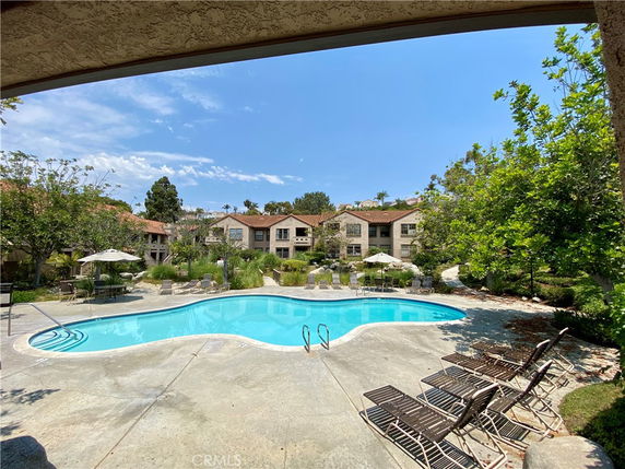 Outdoor swimming pool area with lounge chairs and surrounding residential buildings.