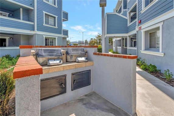 Front view of a multi-story residential building with a shared outdoor grill area.
