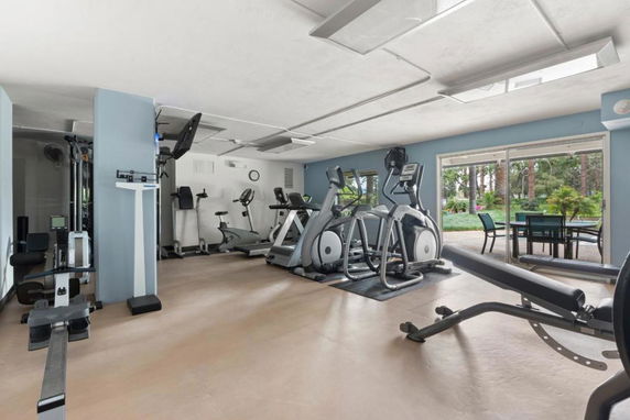 Indoor gym area with exercise equipment and a view through large windows.