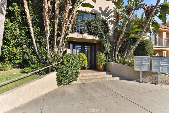 Front view of a multi-story building entrance with plants on either side.