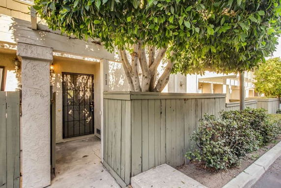 Entrance view of a residence with a wooden fence and a tree.