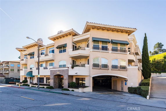 Front view of a multi-story building with balconies and awnings.