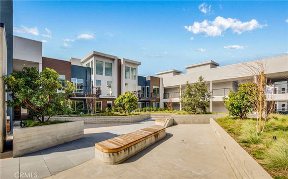 Front view of a modern apartment complex with multiple stories and large windows, surrounded by landscaped areas.
