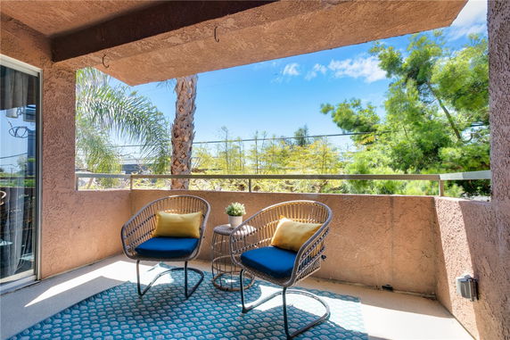 Balcony view with chairs overlooking trees and clear sky.