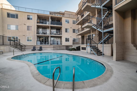 Outdoor swimming pool surrounded by multi-story apartment buildings.